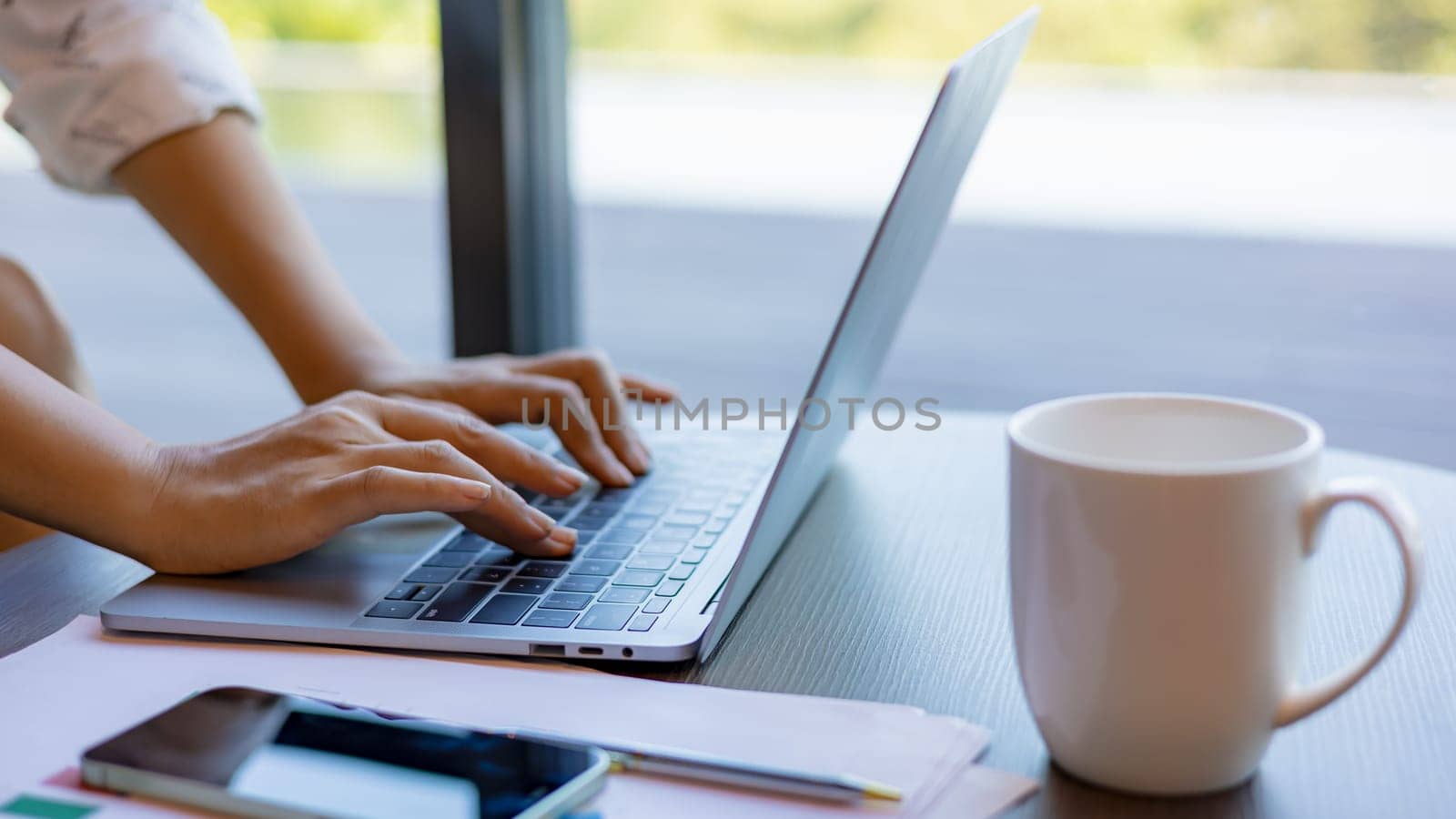 Female hands typing on laptop computer keyboard on wood desk at office, Technology, Business concept. Business woman analyze the graph of the company performance to create profits and growth.