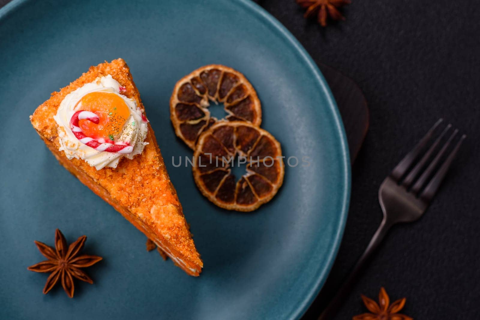 Piece of sweet layer cake with pumpkin or citrus flavor with cream on a dark textured background