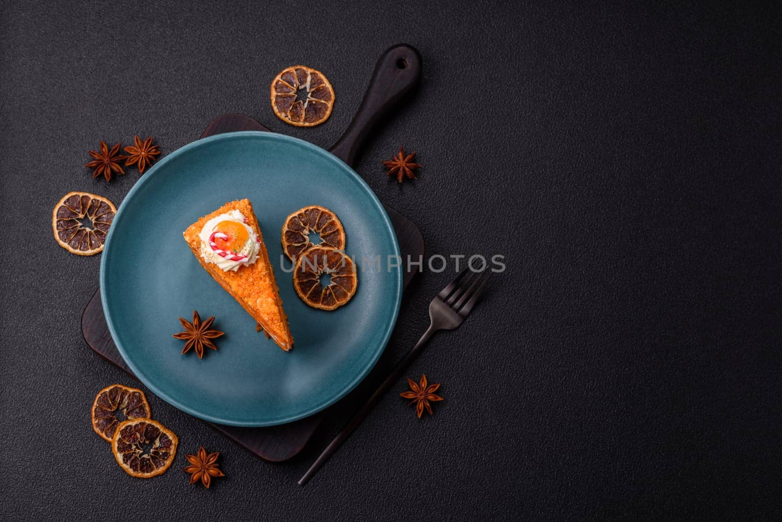 Piece of sweet layer cake with pumpkin or citrus flavor with cream on a dark textured background