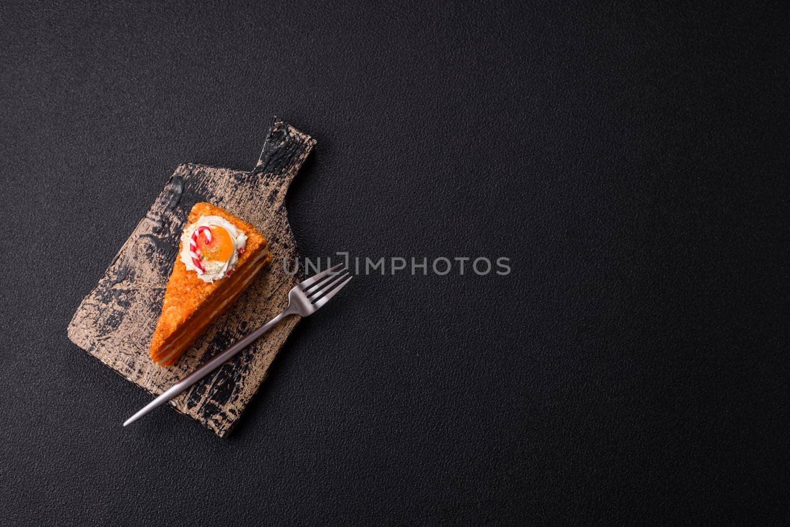 Piece of sweet layer cake with pumpkin or citrus flavor with cream on a dark textured background