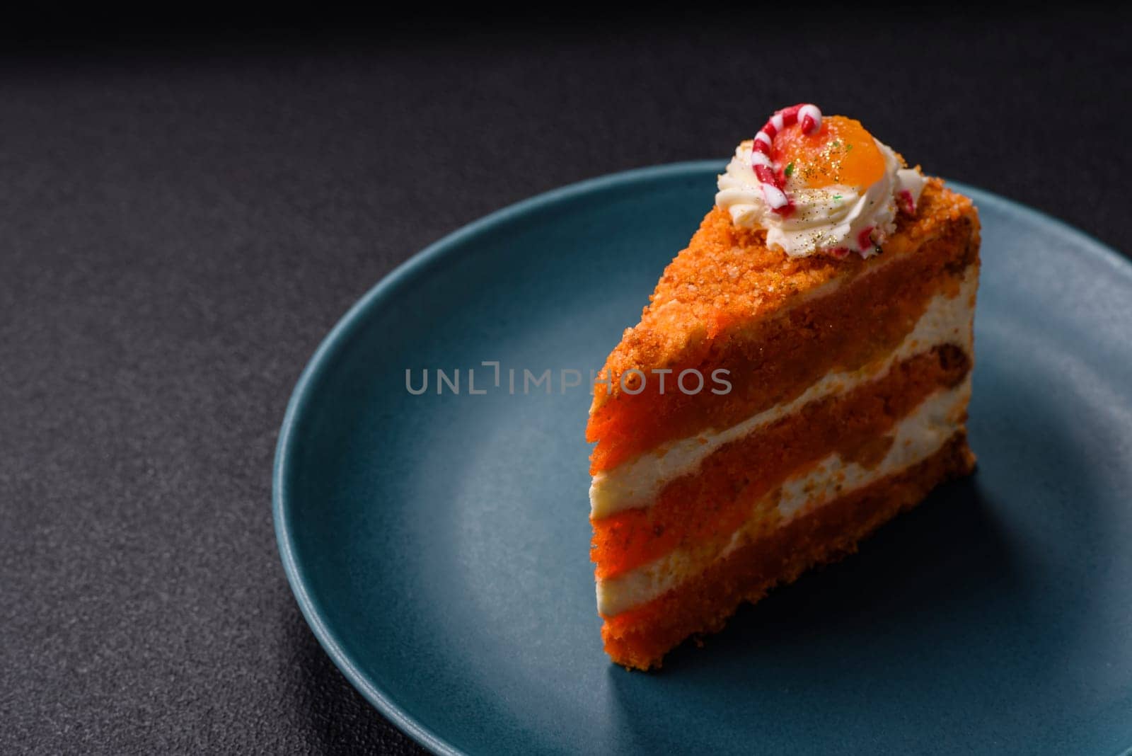 Piece of sweet layer cake with pumpkin or citrus flavor with cream on a dark textured background
