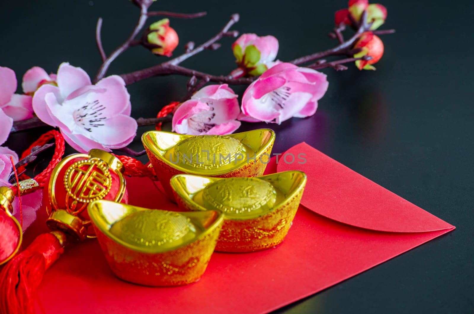 Golden Ingots on top of Chinese New Year red packet. Chinese New Year celebration.