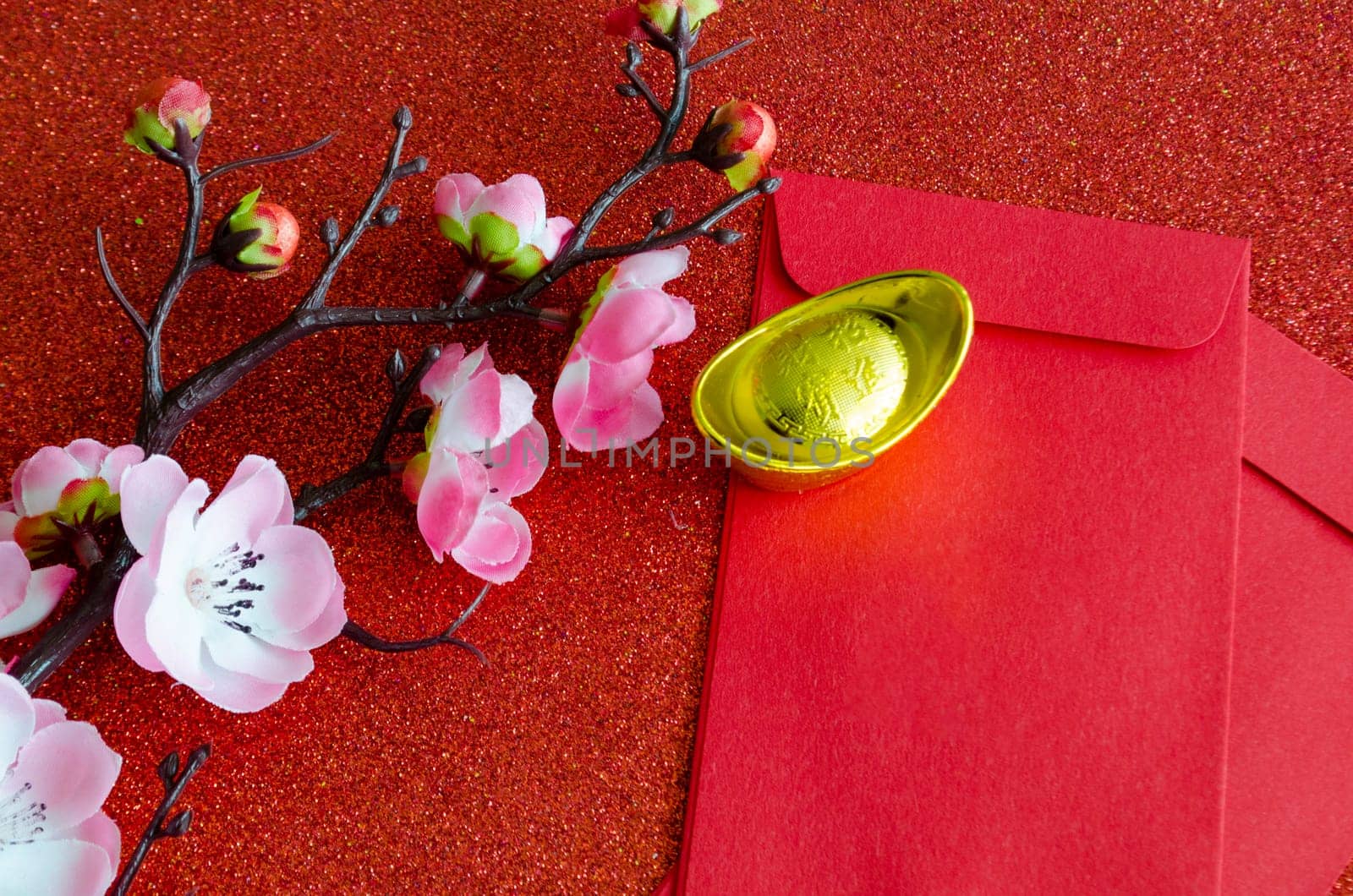 Top view of pink flower, golden ingot and Chinese New Year red packet.