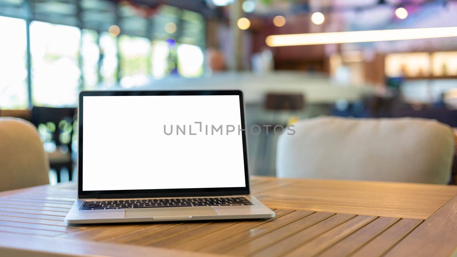 Laptop with blank screen and placed on a wooden table inside a coffee shop. Workspace background new project on laptop computer with blank copy space screen for your advertising text message.