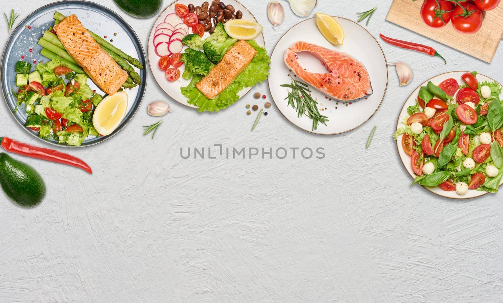 Plates with fried and raw salmon pieces, avocado and spices on white background, top view. Copy space
