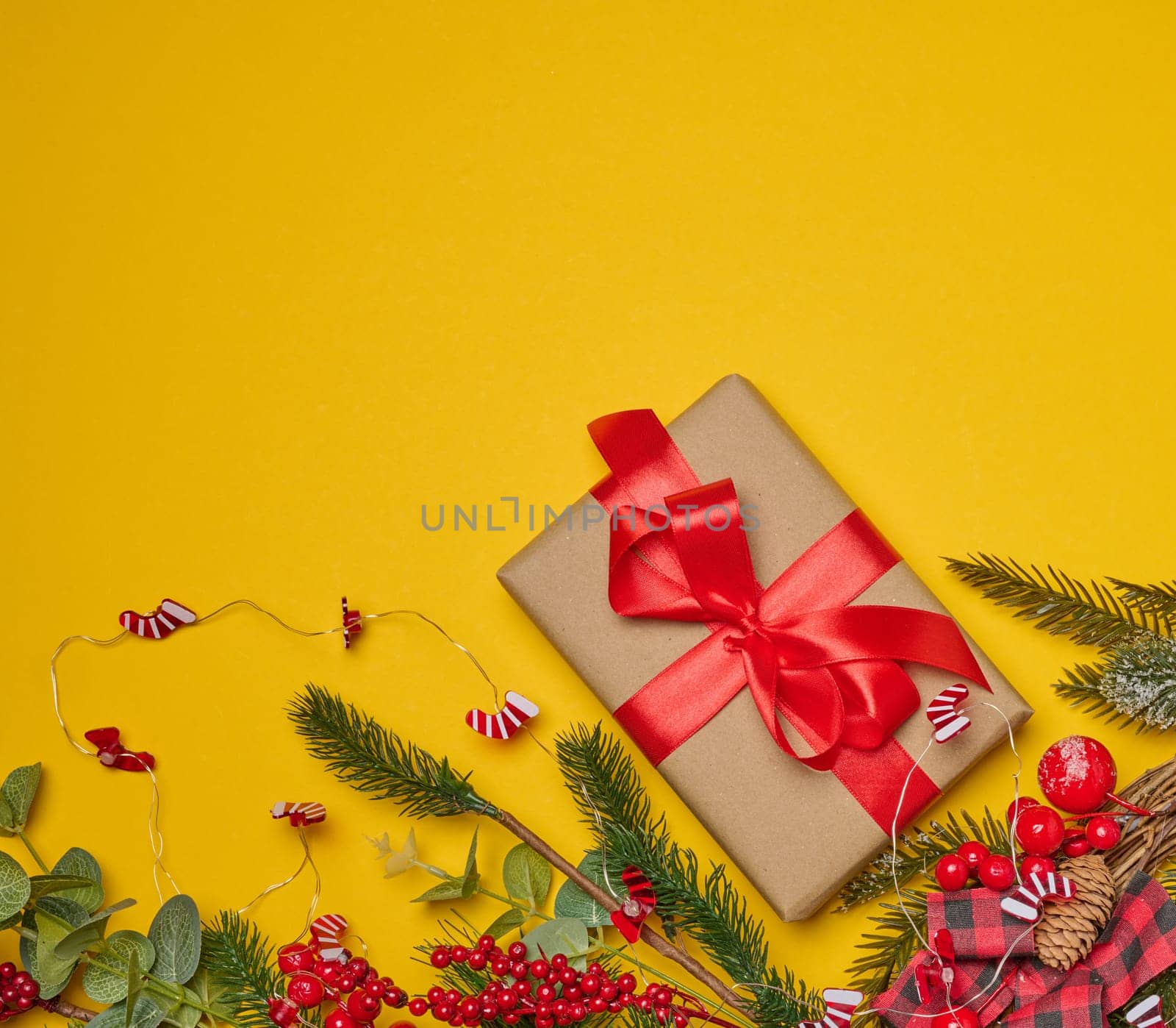 Christmas background, wrapped gift in brown paper and red silk ribbon, top view. Copy space