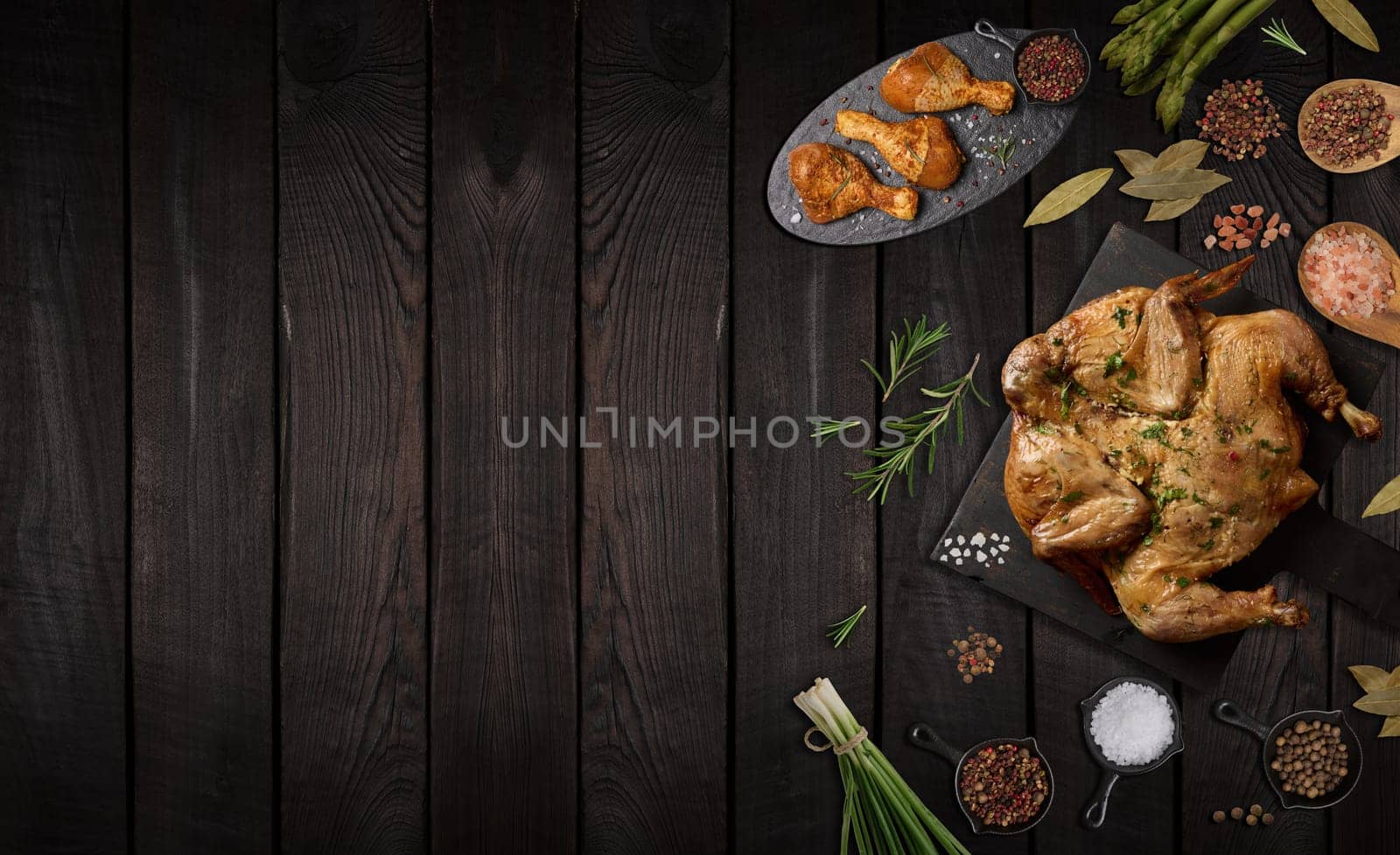Whole fried chicken with spices on wooden board, brown wooden background, top view. Copy space