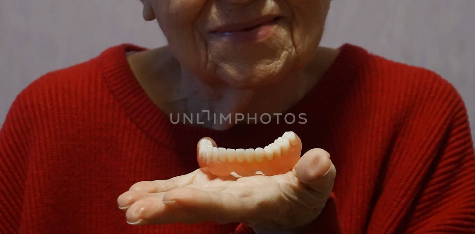 flexible nylon denture on senior female hands. Removable dentures flexible, devoid of nylon, hypoallergenic exempt from monomer