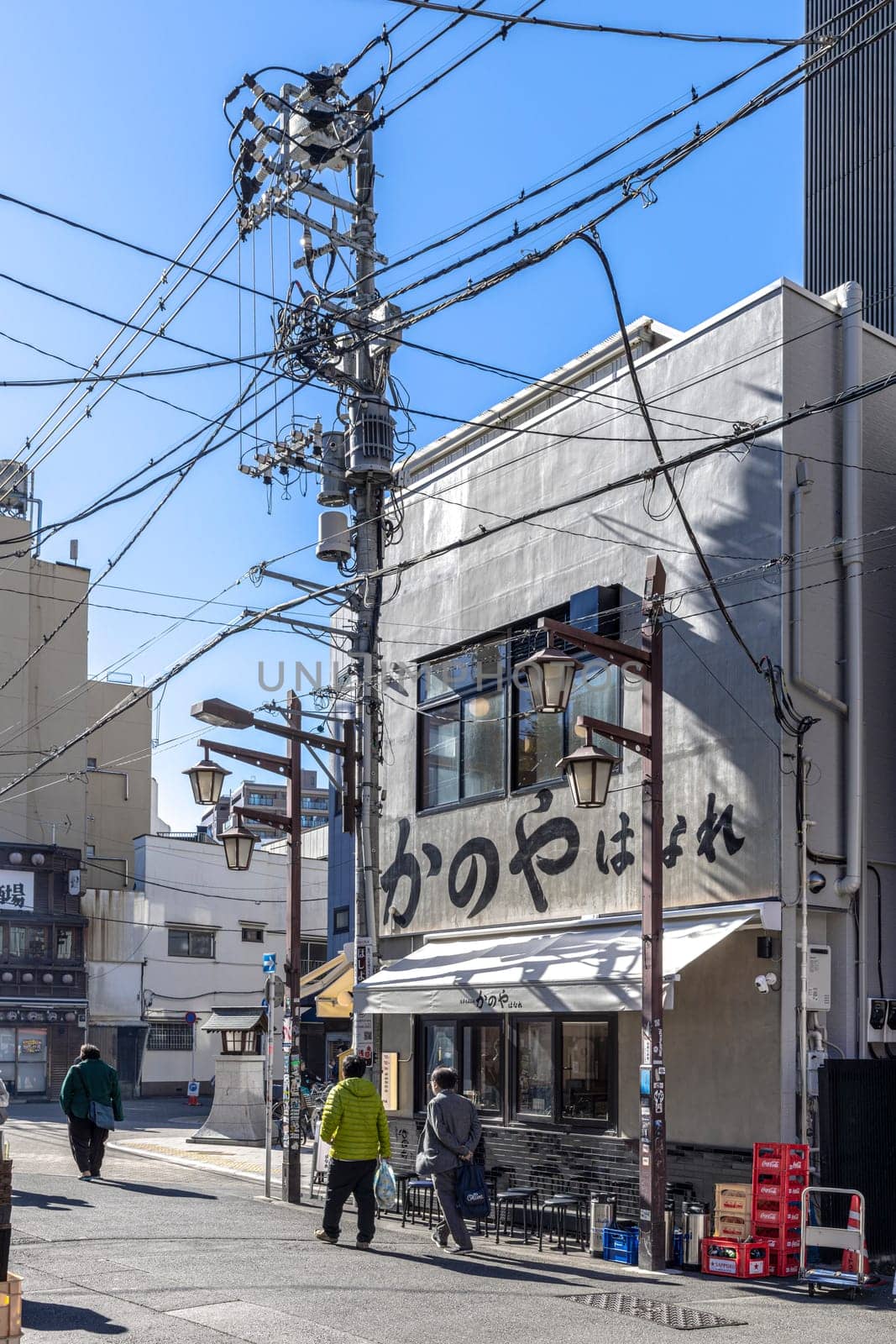 People walking on a typical japanese street with messy power lines and restaurant