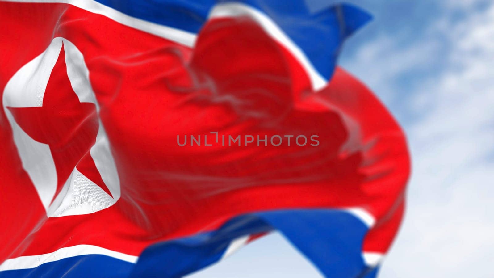 Close-up of North Korea national flag waving in the wind on a clear day. Red flag with star and blue white stripes. 3d illustration render, Rippling fabric. Selective focus