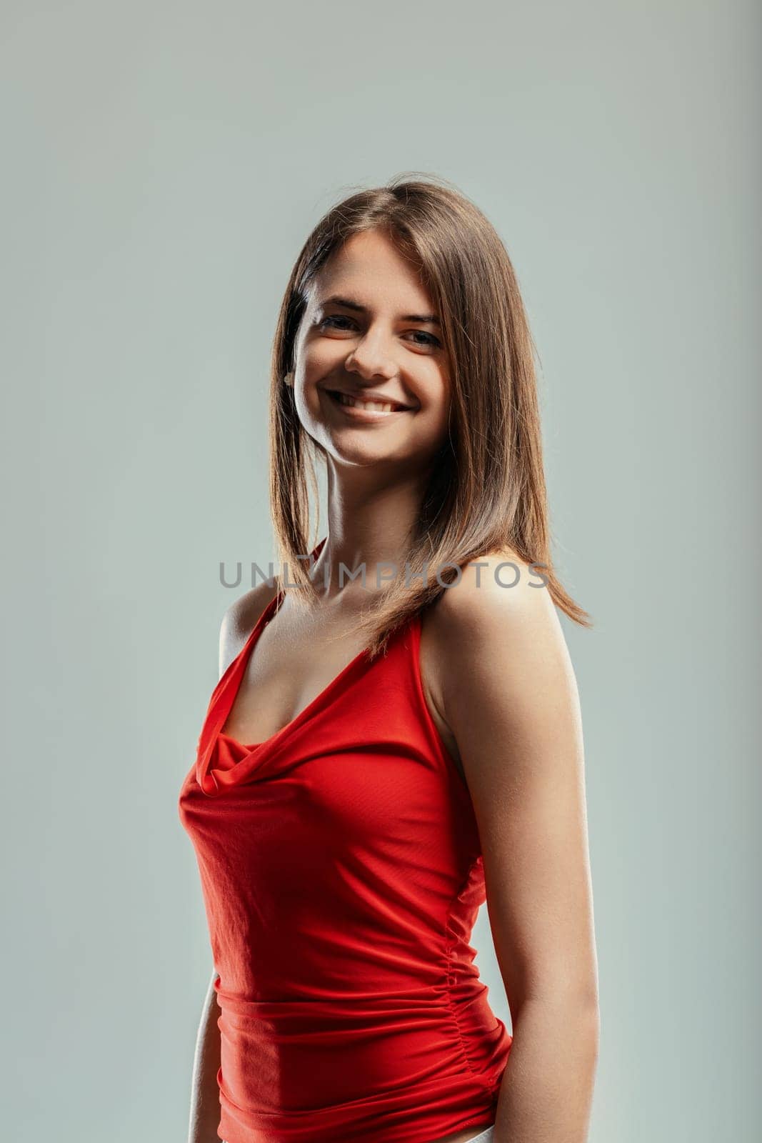 Portrait of a beautiful young woman wearing a striking red top, smiling brightly and looking directly at the camera, radiating confidence and embracing self-acceptance
