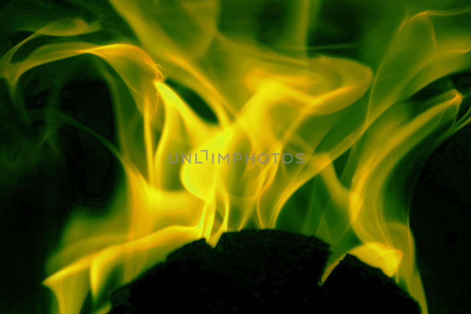 Flames from a fire in green and gold against a black background
