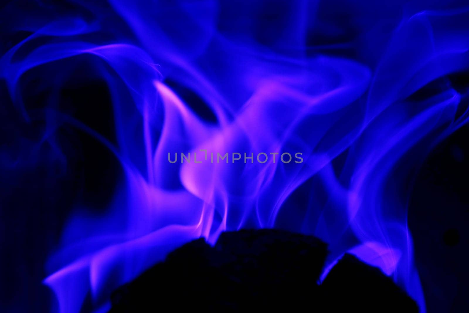 Flames from a fire in blue and pink against a black background
