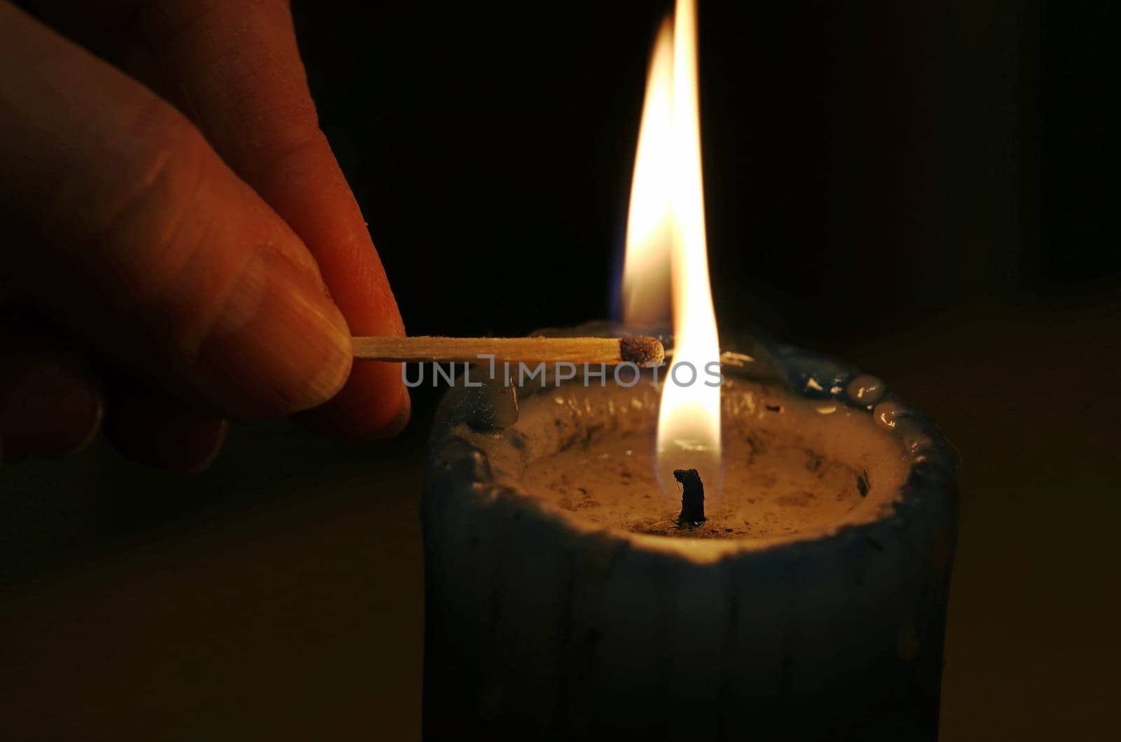A woman lights a candle in the dark