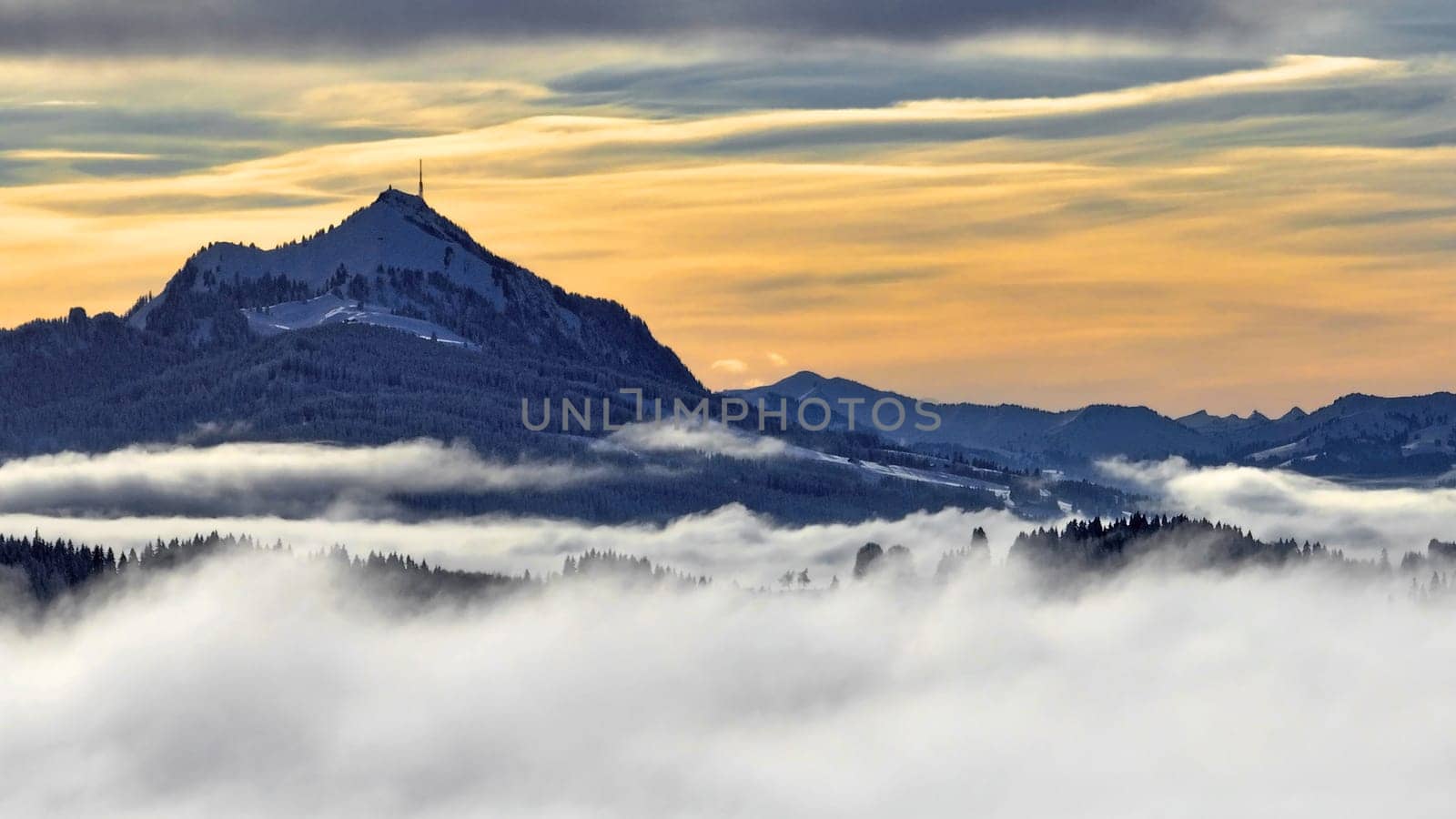 Drone shot in winter with fog in the valley and sun in the mountains at sunset