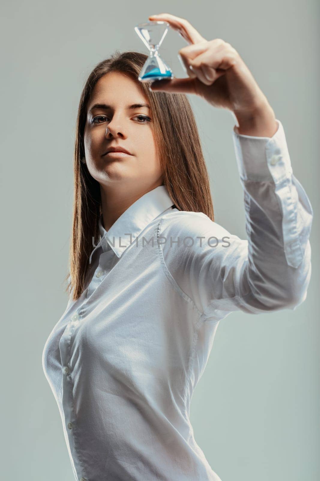 Young businesswoman holding a small hourglass while looking at the camera, representing time management, efficiency, and the importance of meeting deadlines in a professional setting