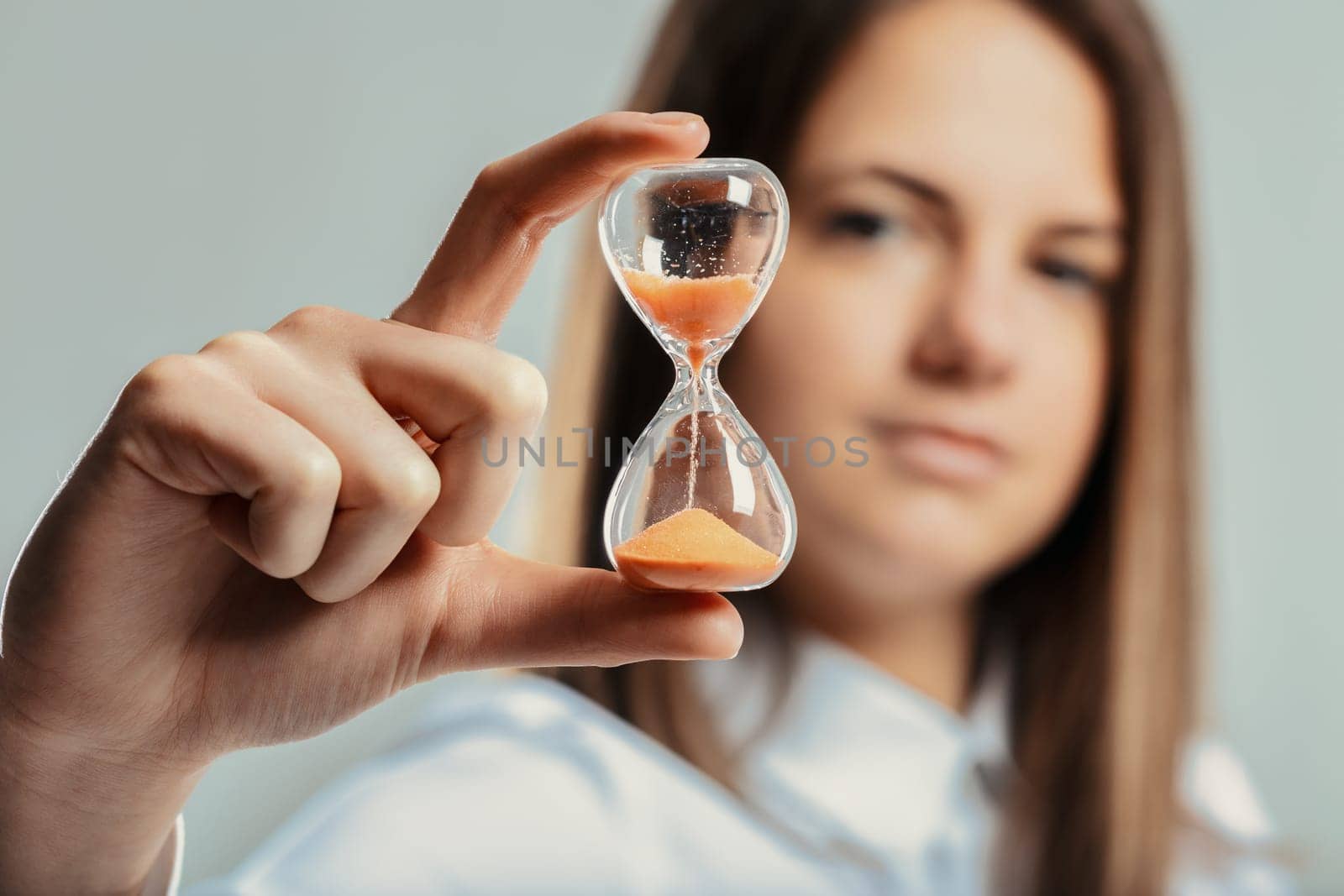 Businesswoman holding an hourglass, symbolizing time management, deadlines, and the importance of efficient work practices in a corporate setting