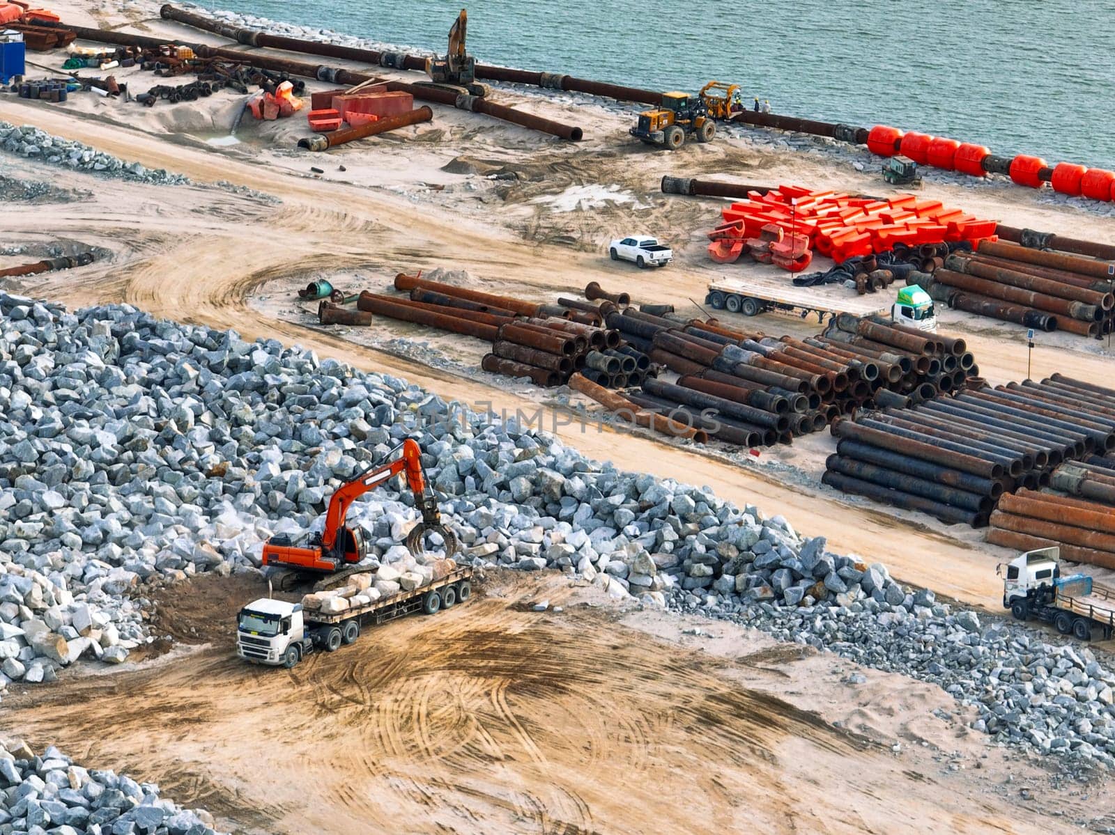 Construction progress on shipping port terminal through land reclamation. Global trade development, infrastructure engineering, and marine environmental sustainability efforts. Maritime infrastructure