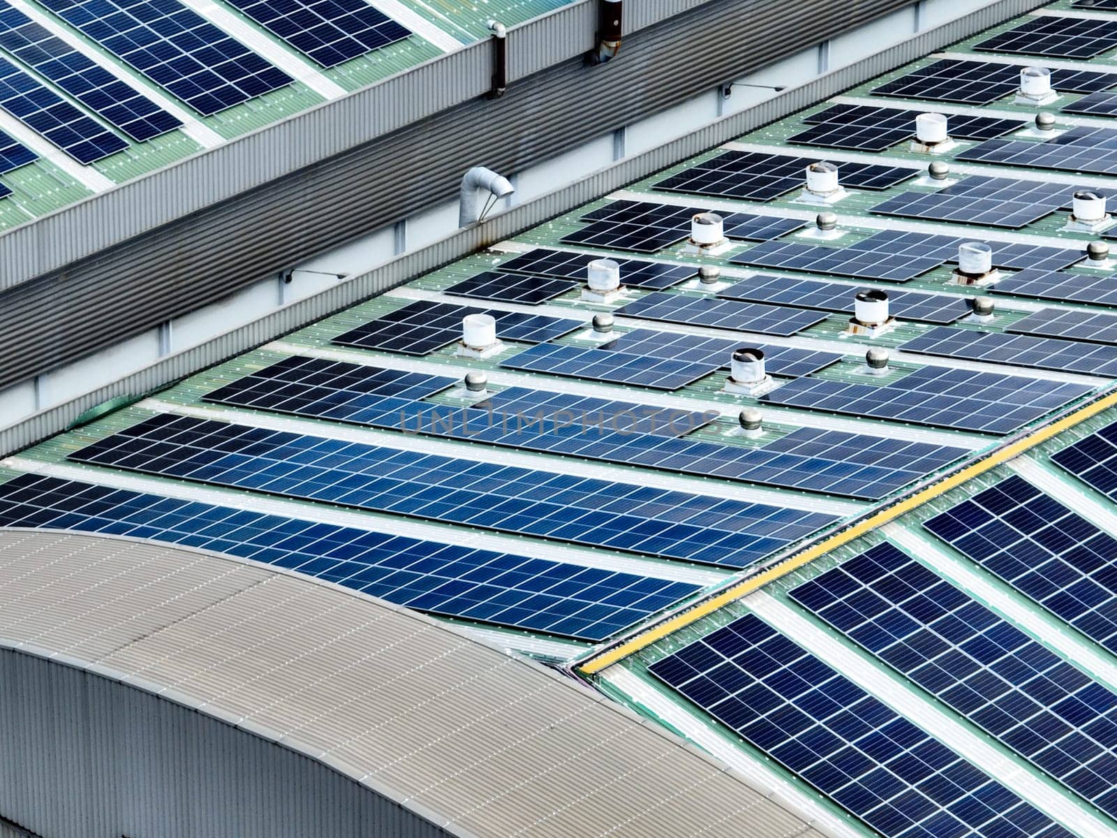 Rooftop solar panels on an industrial plant building. Clean and renewable power solutions, green energy innovation, and sustainable commercial electricity generation. Sustainable manufacturing.