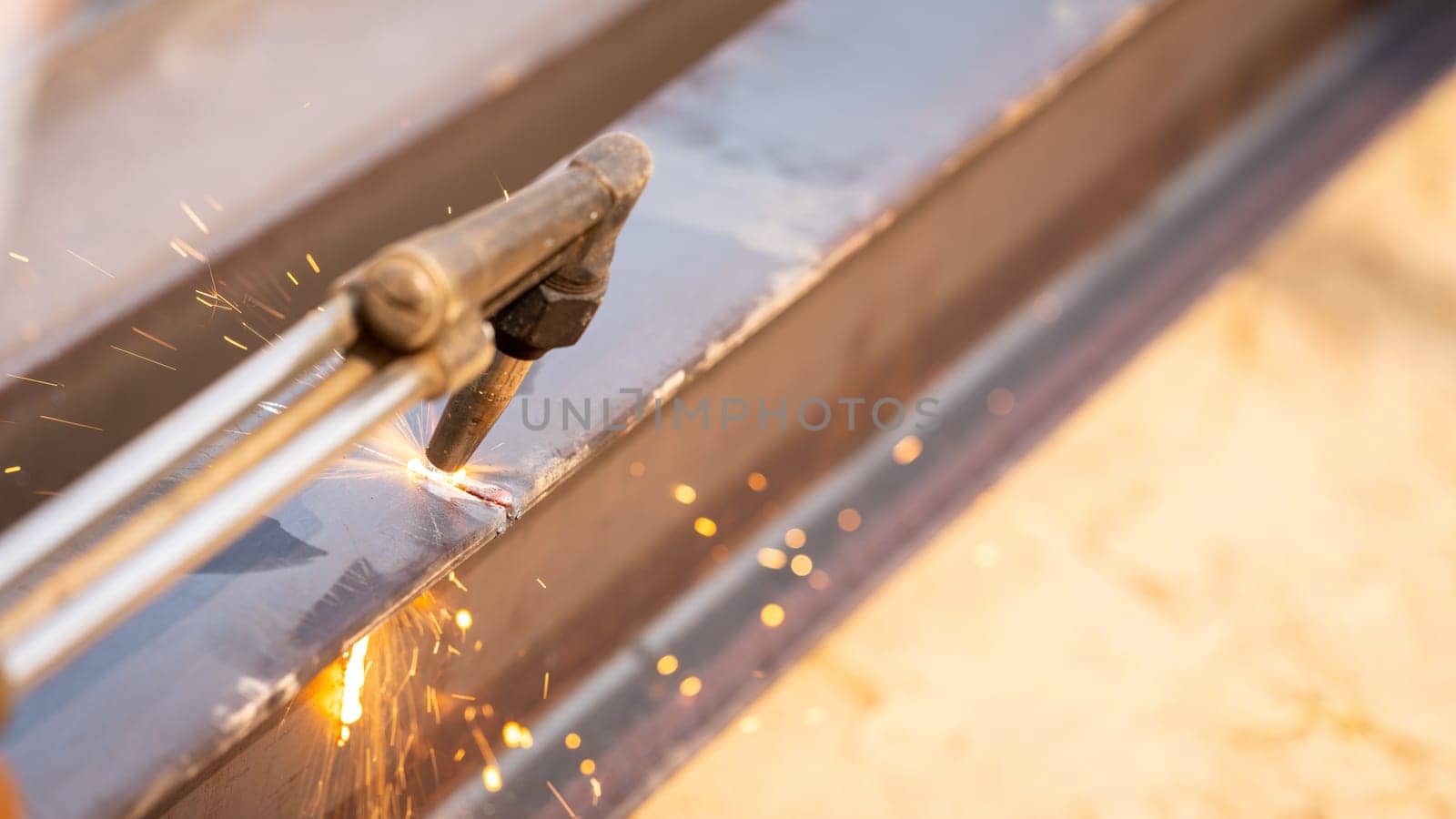 Skilled metalworker uses torch to cut through steel. Sparks fly as craftsman demonstrates precision in industrial workshop. Concept of balancing risk and expertise in dangerous metalworking processes.