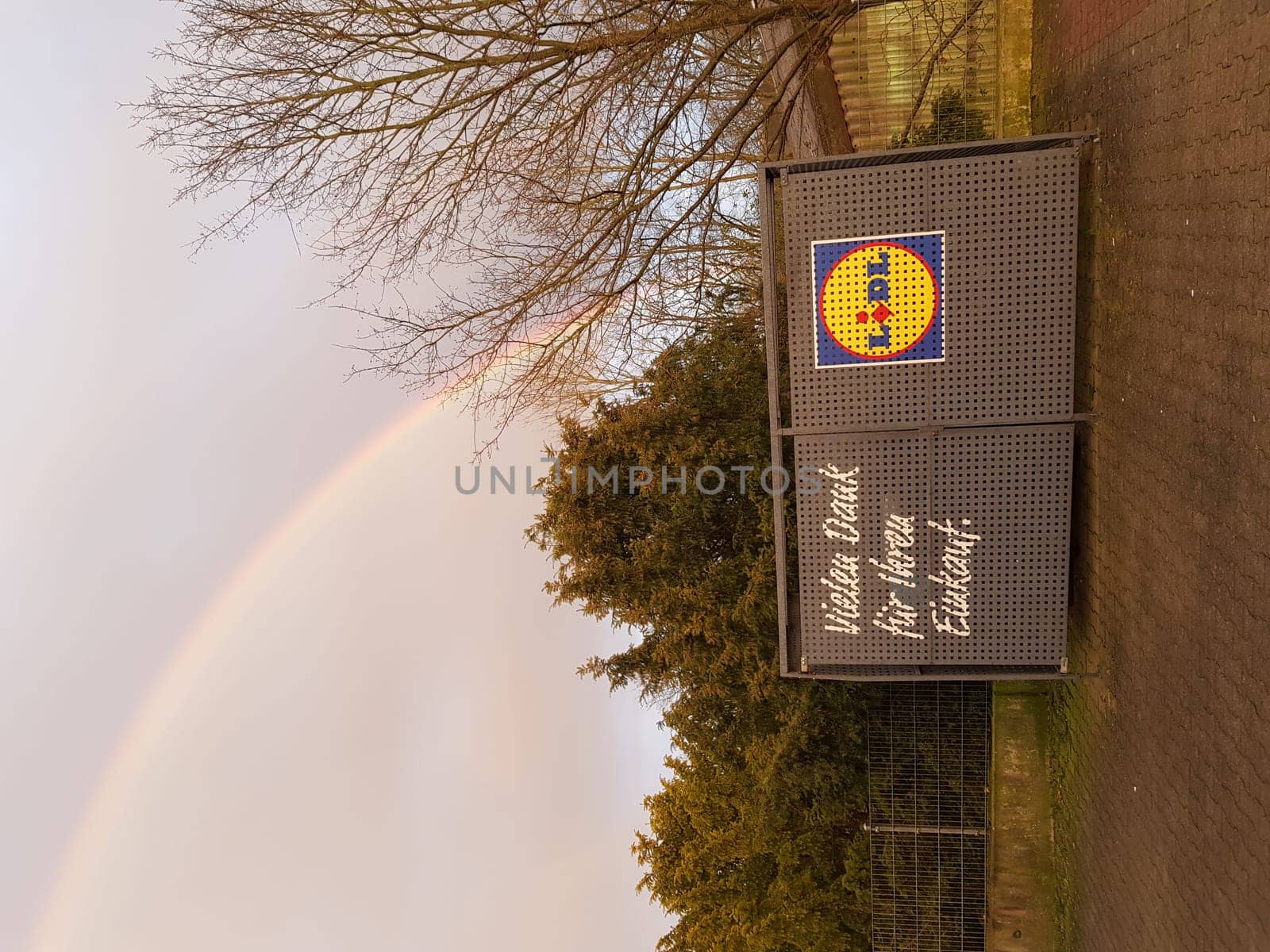 ESSEN HEIDHAUSEN, NRW, GERMANY - MARCH 10, 2020: Essen Heidhausen, Nrw, Germany - March 10, 2020: Lidl supermarket car park in Essen Heidhausen, Ruhr area, view across the street to an advertising sign from Lidl with lettering in German Thank you for your purchase. A rainbow in the background