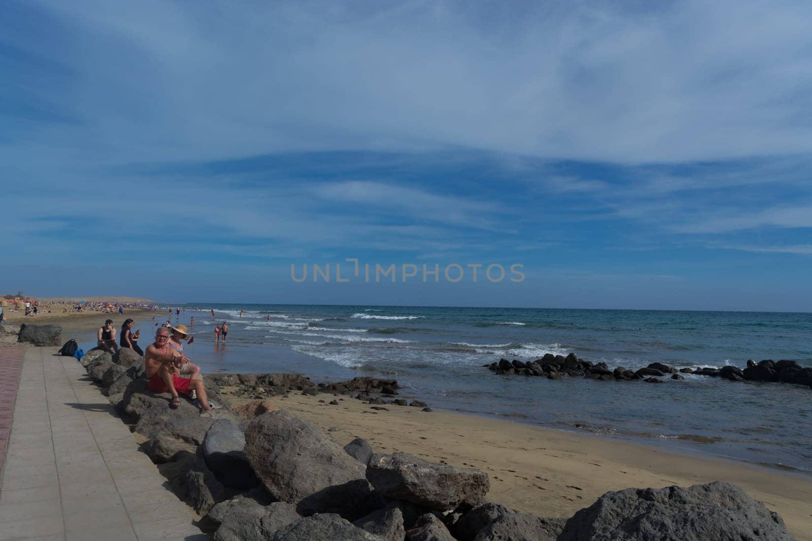 CRAN CANARIA, MELONERAS - NOVEMBER 13, 2019: Cran Canaria, Meloneras, Spain - November 13, 2019: People enjoy the sea view and sit in the sun on the seafront of Meloneras on Gran Canaria, Spain