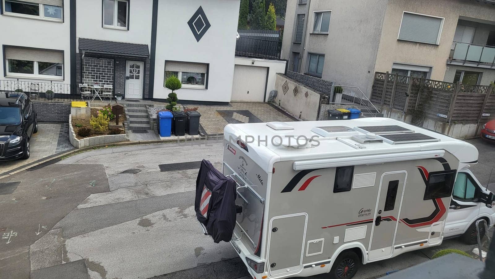 HEILIGENHAUS, NRW, GERMANY - AUGUST 06, 2022: Heiligenhaus, Nrw, Germany - August 06, 2022: Camping and tourism theme. Modern camper van with solar panels installed staying on the cobblestone driveway waiting for a new destination. aerial view