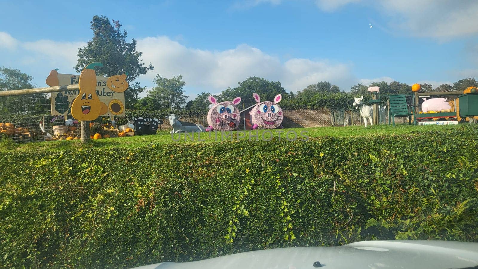 A picturesque farm scene with hay bale pigs, pumpkins, and a sign welcoming visitors.