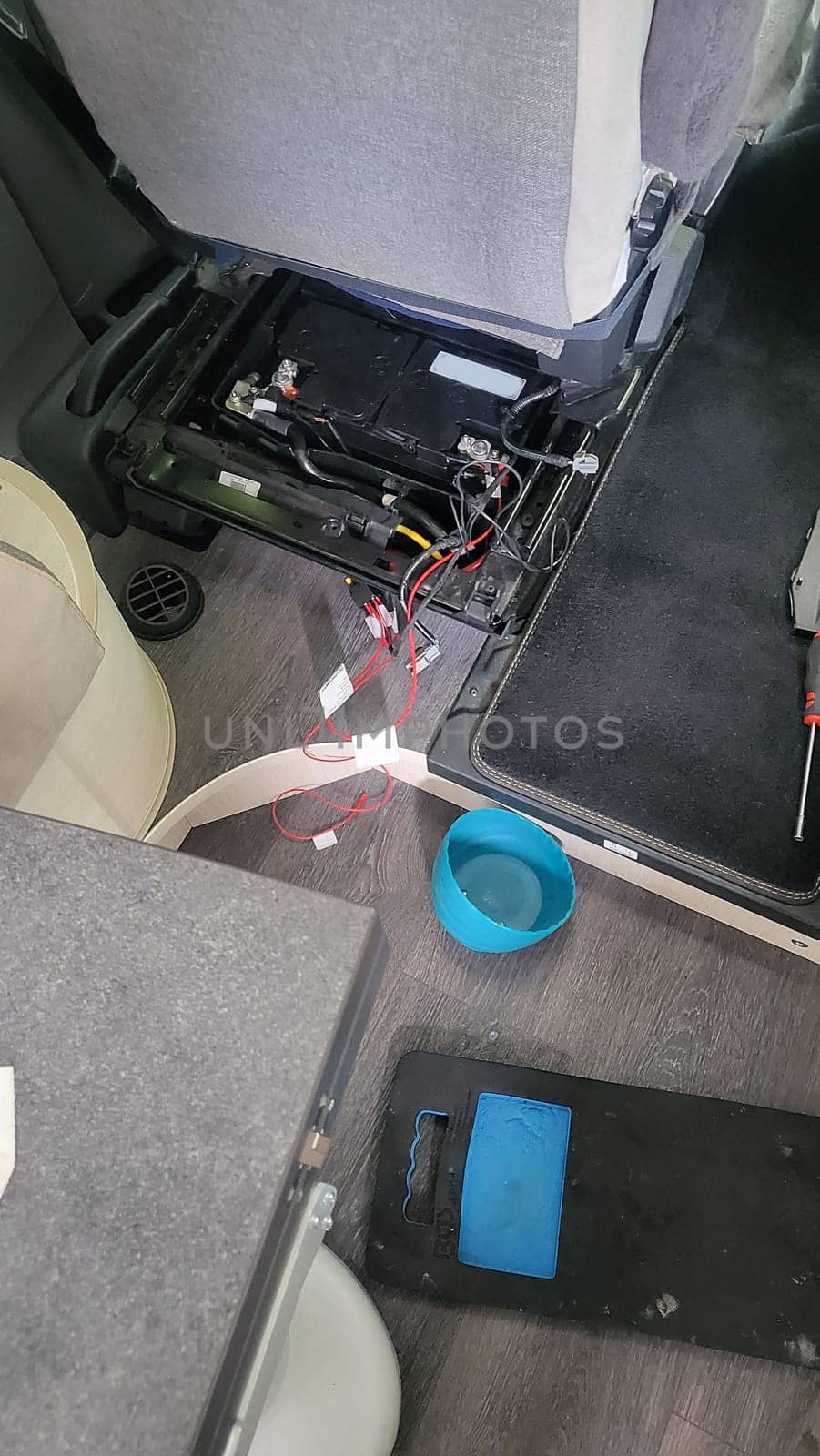 working on the electrical system of a car, with wires, a battery, and tools visible.