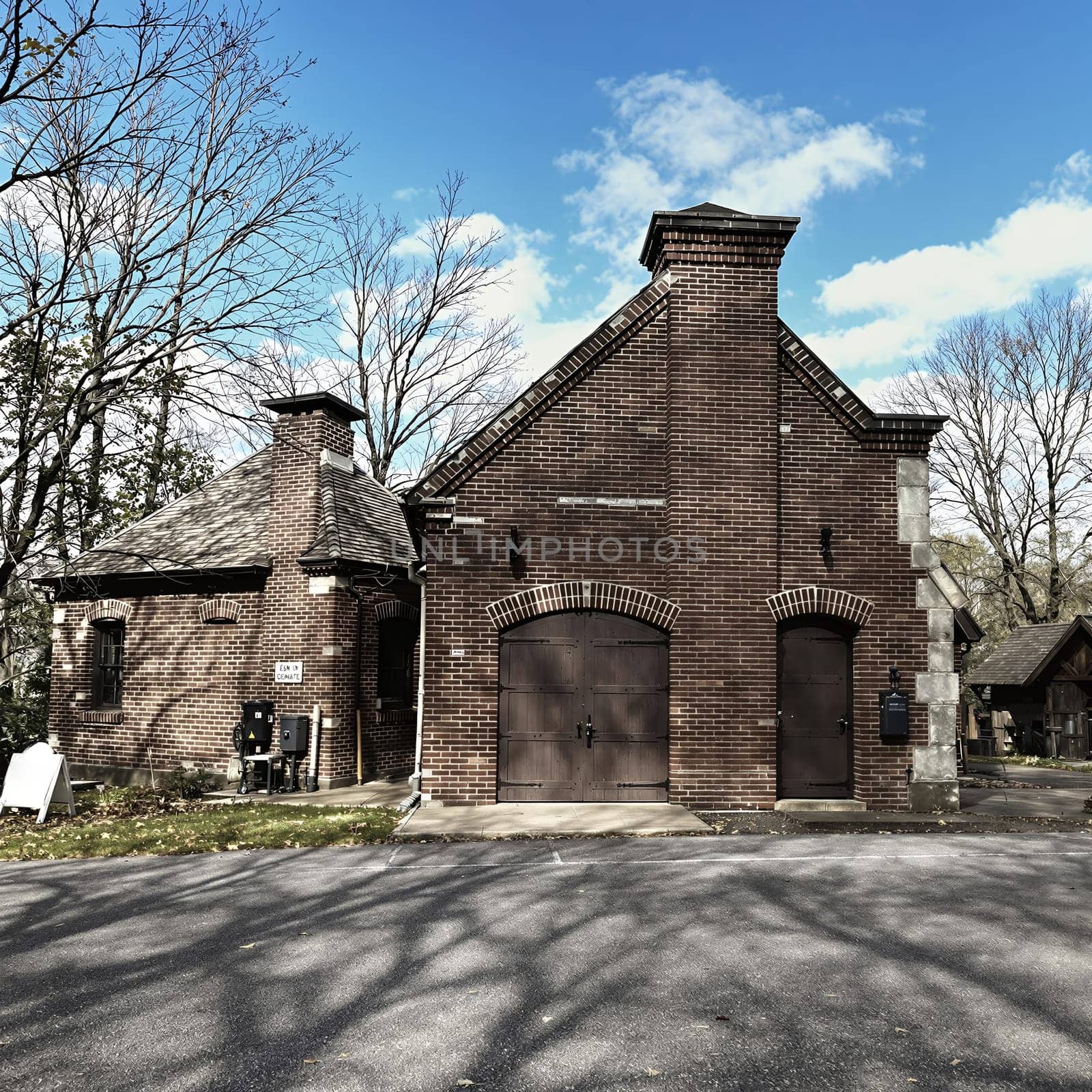 Historic brick building with twin chimneys and blue sky in autumn.