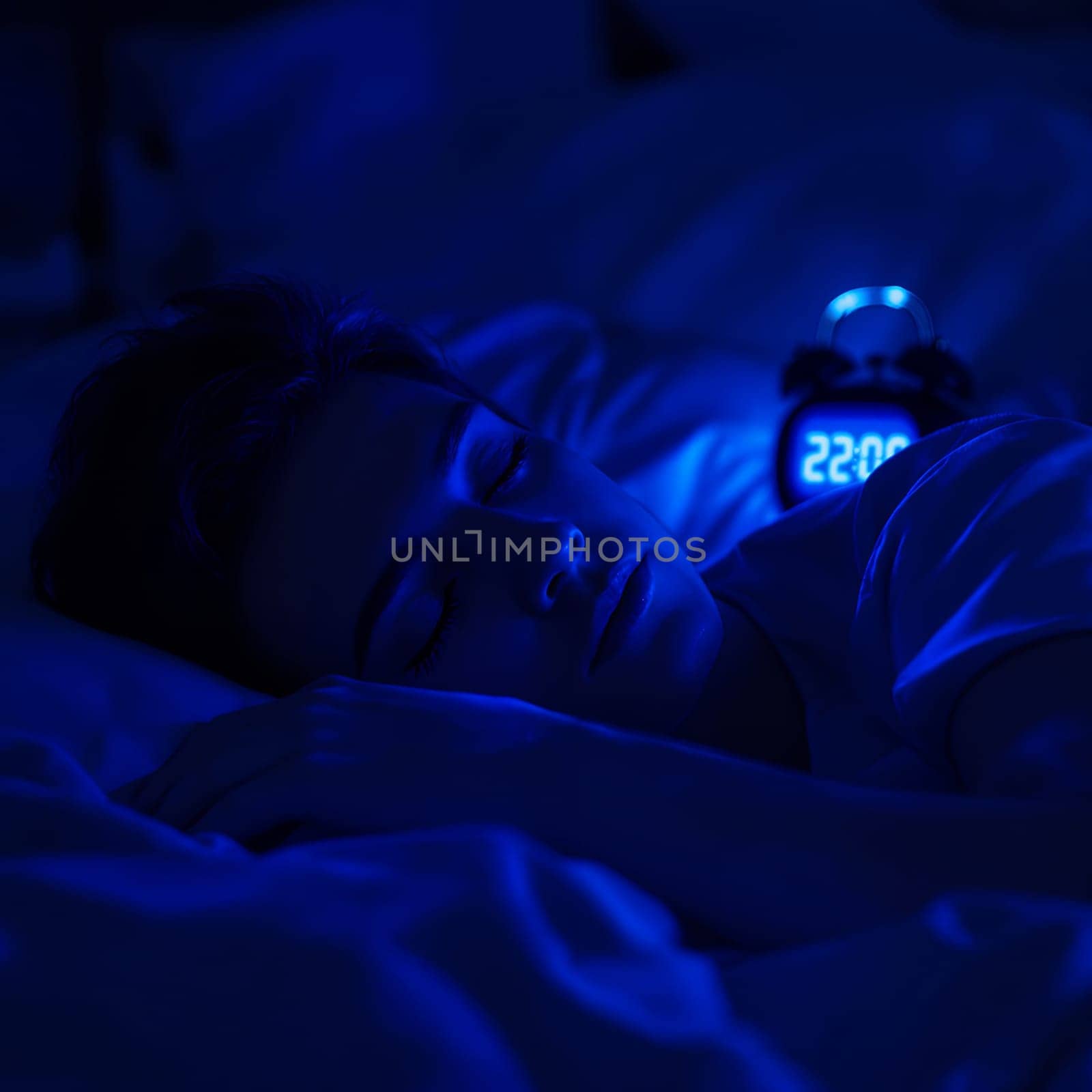 Young caucasian female sleeping peacefully at night with digital clock displaying 22:00.