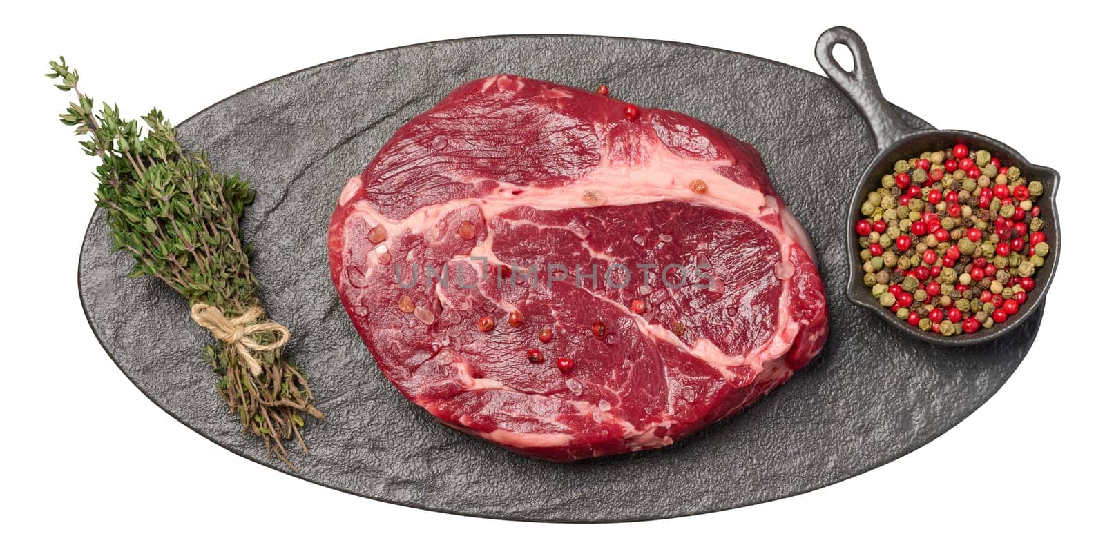 Raw piece of beef and sprig of thyme on black oval board, top view. Isolated background