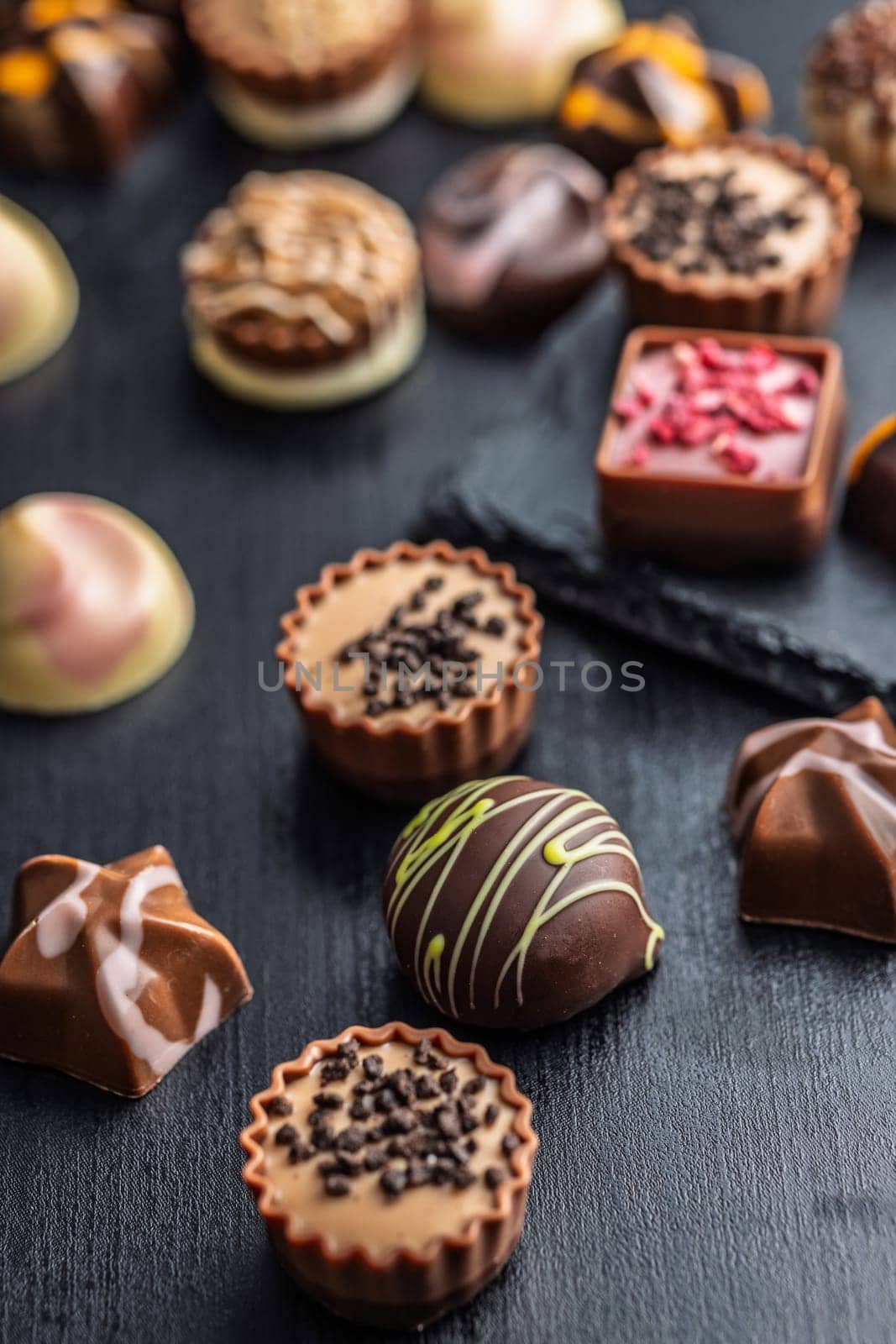 Mix of chocolate pralines on a black table.
