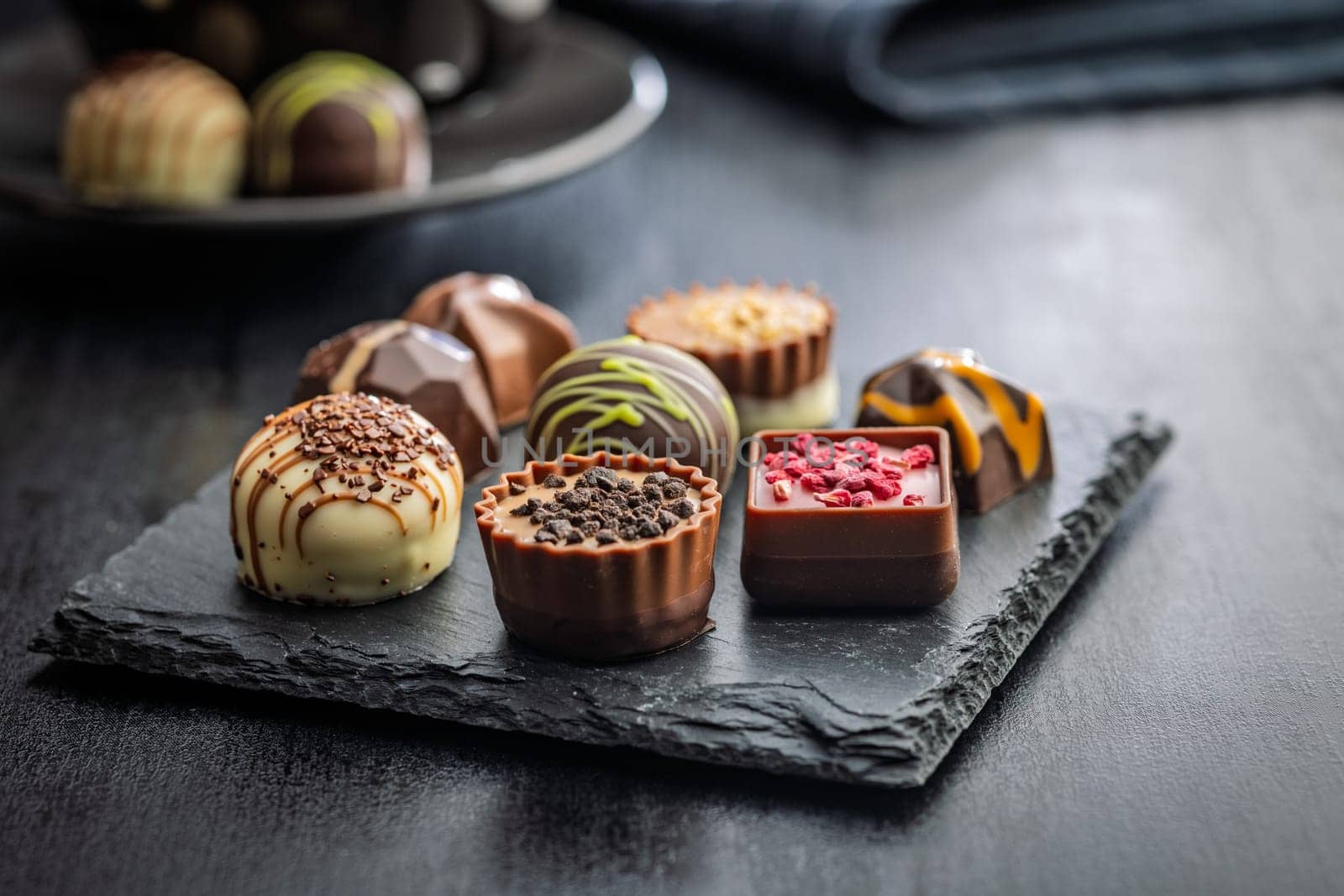 Mix of chocolate pralines on a black table.
