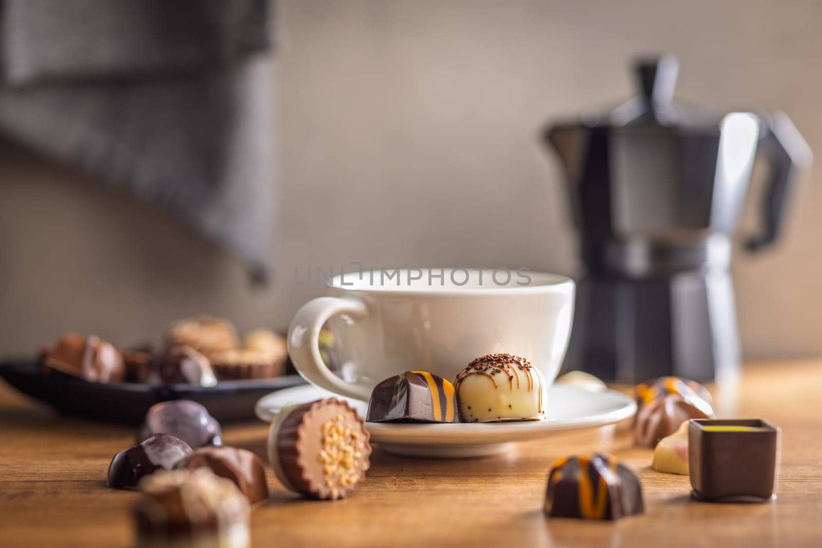 Mix of chocolate pralines and coffee cup on a wooden table.
