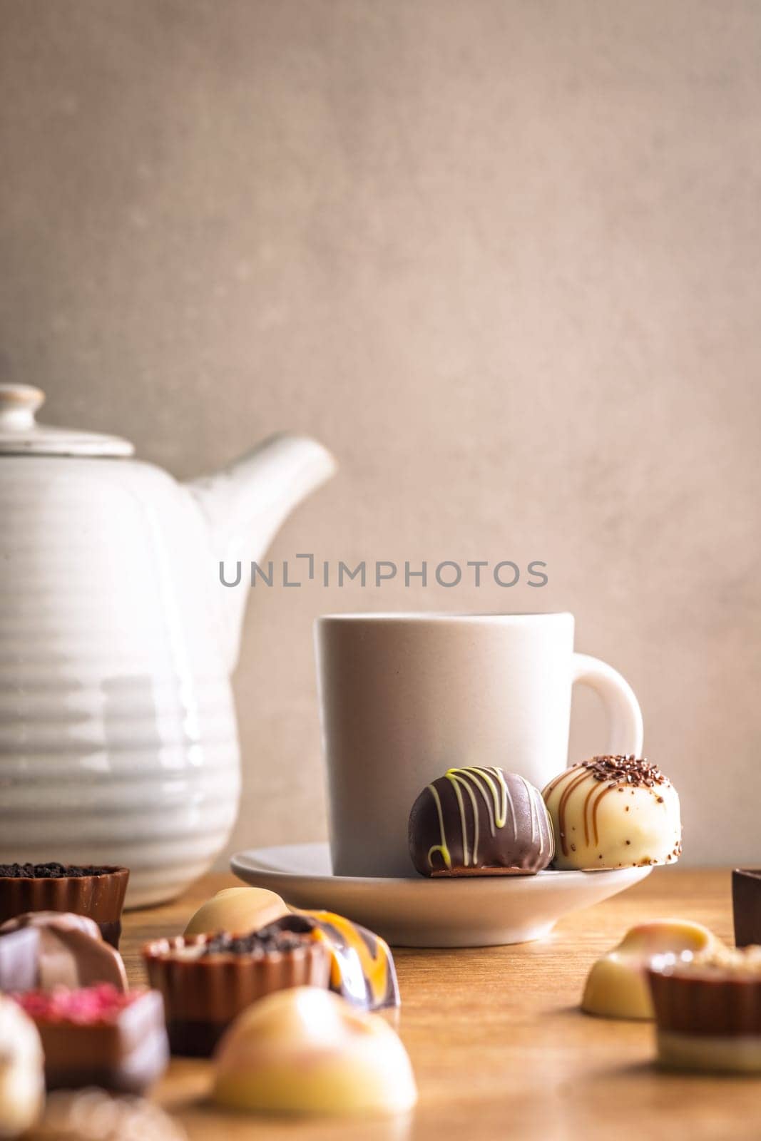 Mix of chocolate pralines and coffee cup on a wooden table.