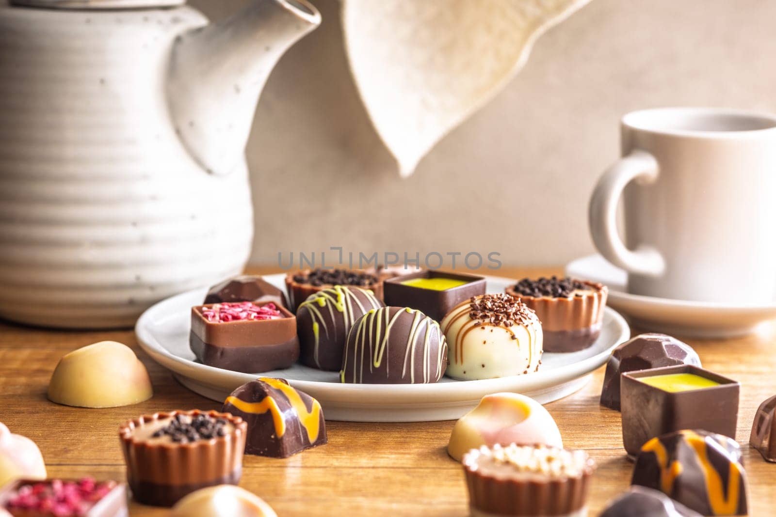 Mix of chocolate pralines on plate on a wooden table.