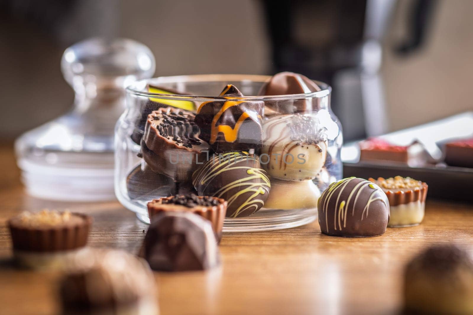 Mix of chocolate pralines in jar on a wooden table.