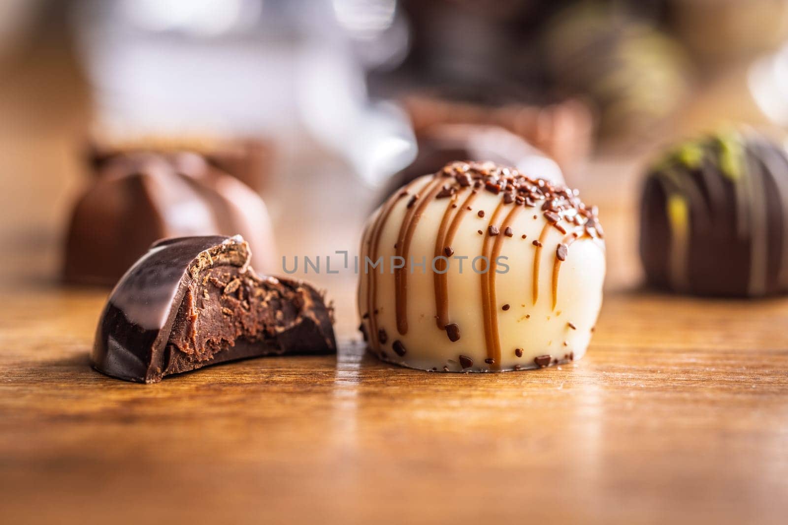 Bitten chocolate praline on a wooden table.