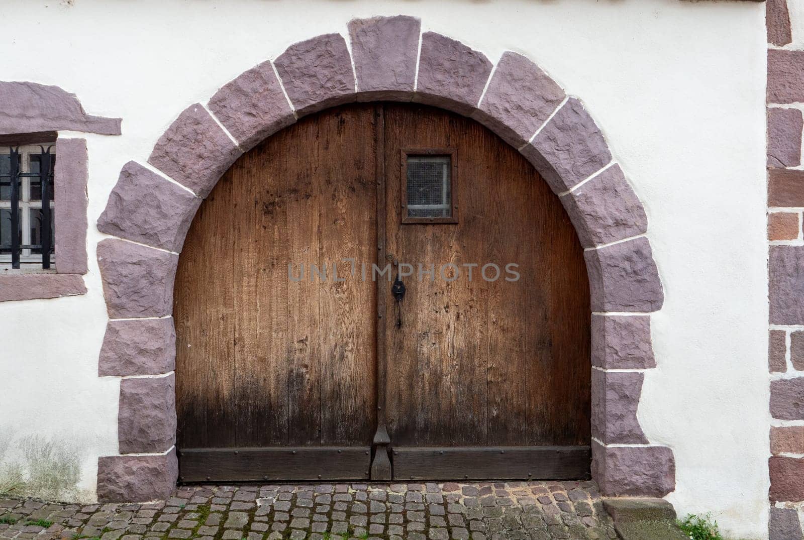 The archway is made of stone and wood. The door is wooden and has a window