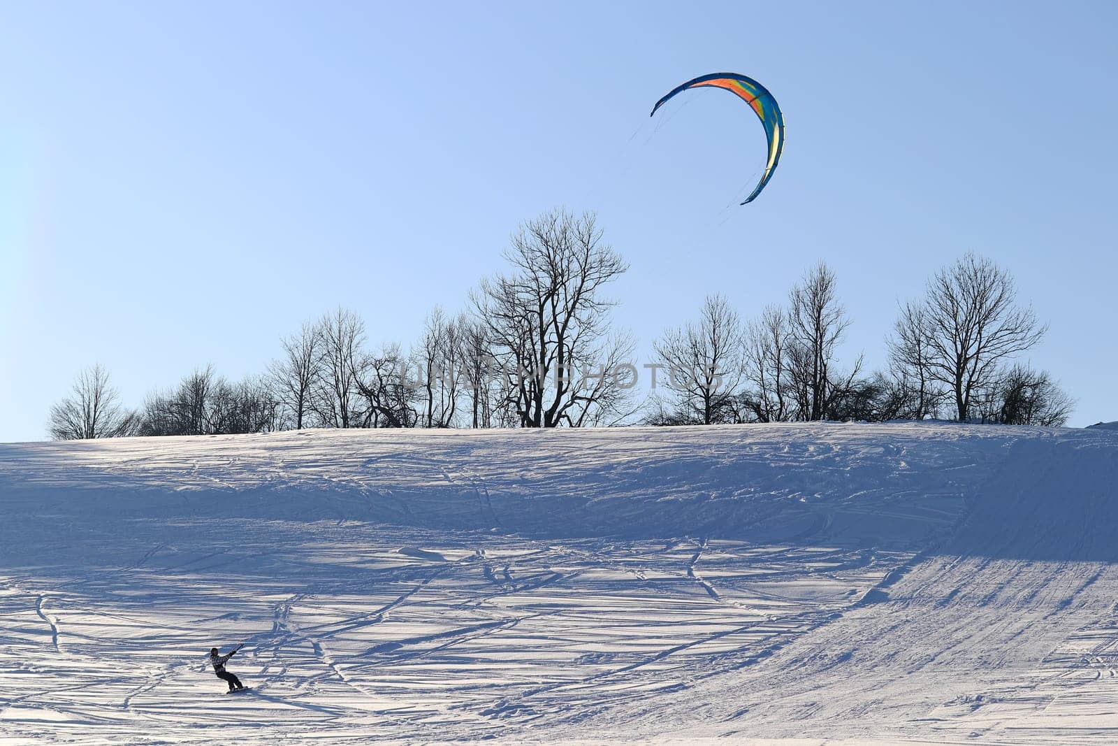 A kitesurfer in winter in the snow. Snowkiting in the mountains