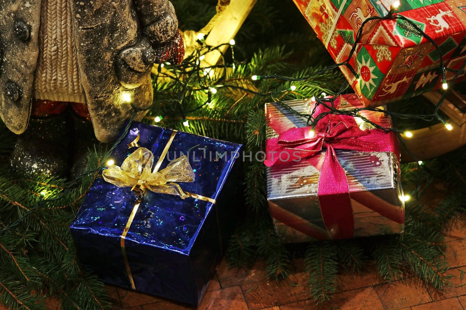 Colorfully wrapped Christmas presents and fairy lights under a Christmas tree