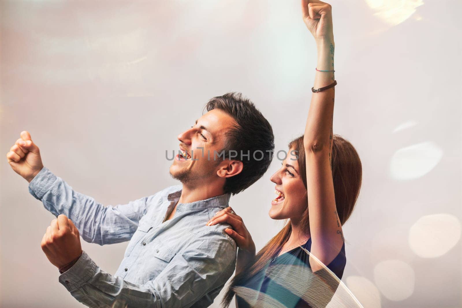 Young couple celebrating together, raising arms in joyful excitement, radiating happiness and positivity. Their ecstatic expressions capture the essence of love and togetherness