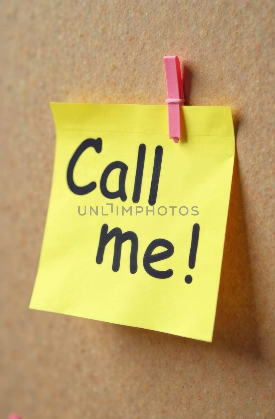 A bright yellow sticky note with bold black text invites someone to call. It is securely pinned to a corkboard, conveying a sense of urgency and communication in a simple yet effective way.