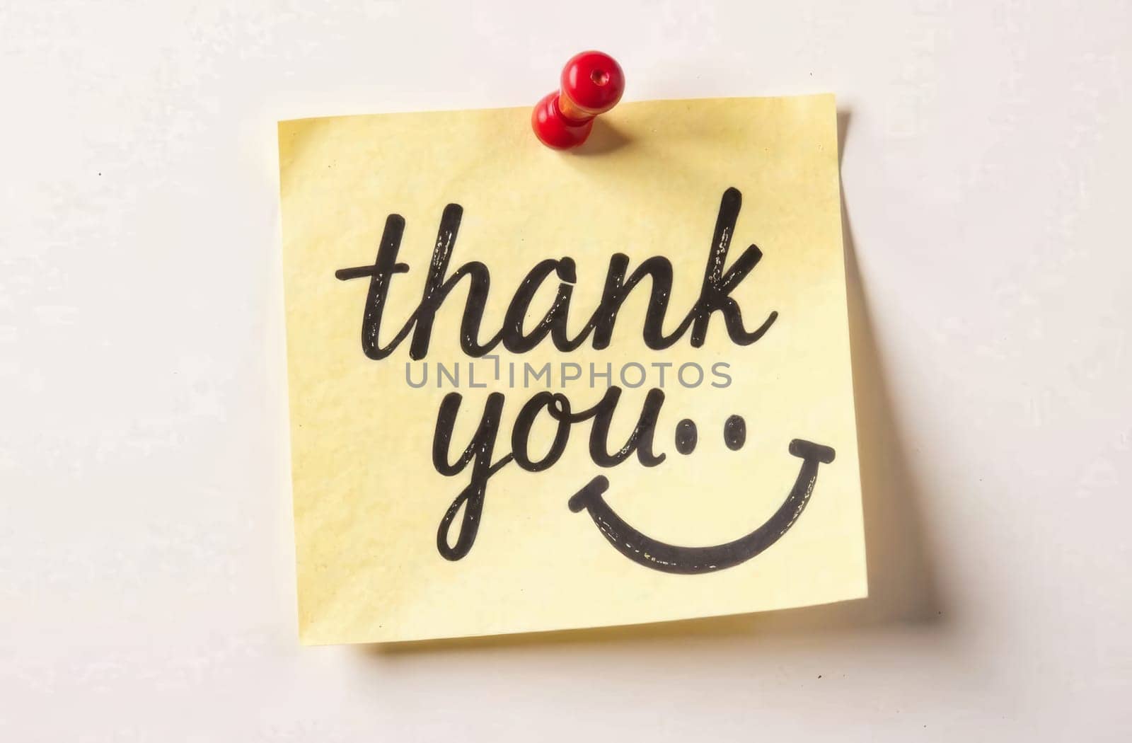 A yellow sticky note with beautifully crafted text expresses gratitude. The note is pinned on a plain background, enhancing its cheerful message and inviting demeanor.