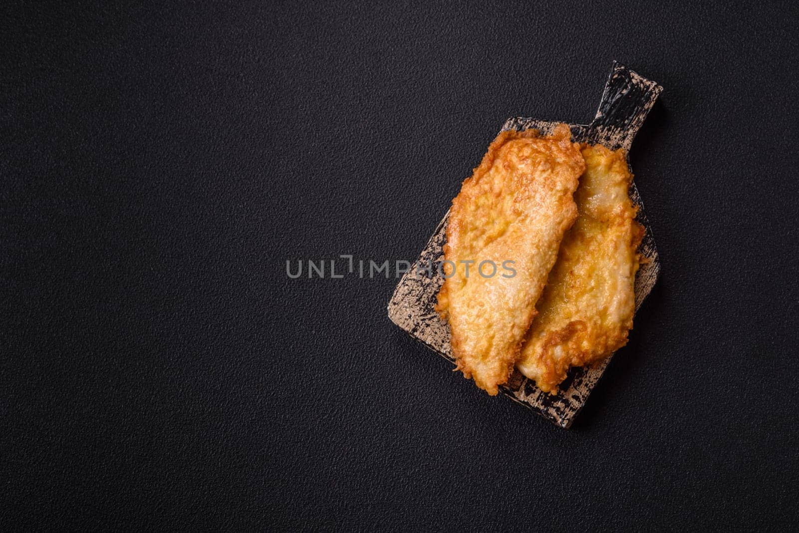 Grilled chicken or turkey chop with salt, spices and herbs on a dark concrete background