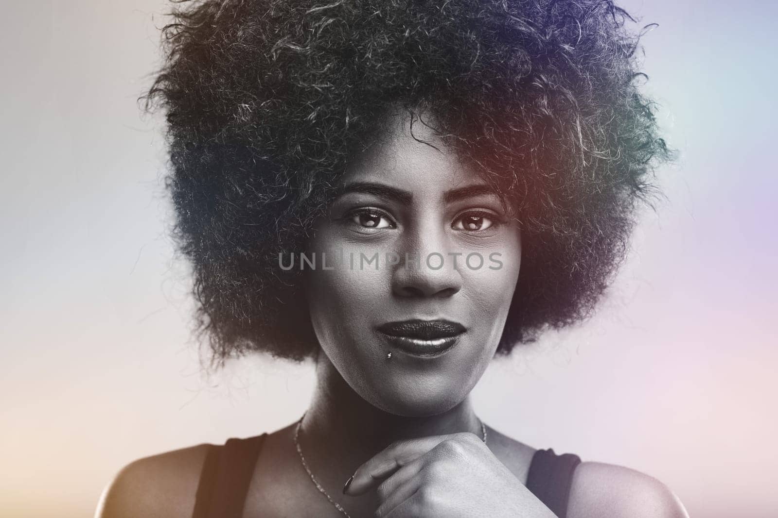 Black and white portrait capturing a beautiful young woman with afro hair, exuding confidence and serenity while gazing directly at the camera with a calm and peaceful expression