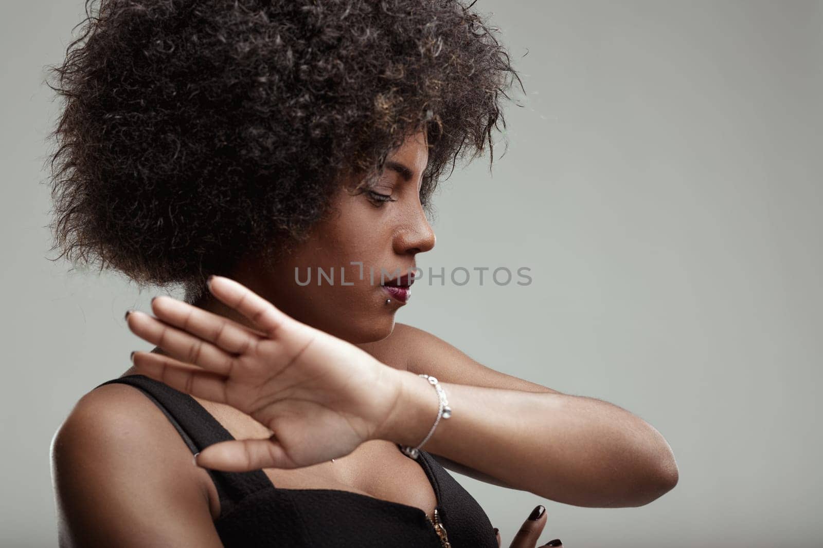Studio portrait of a young latin american woman with curly hair making a stop sign with her hand, expressing a clear message of refusal or setting boundaries