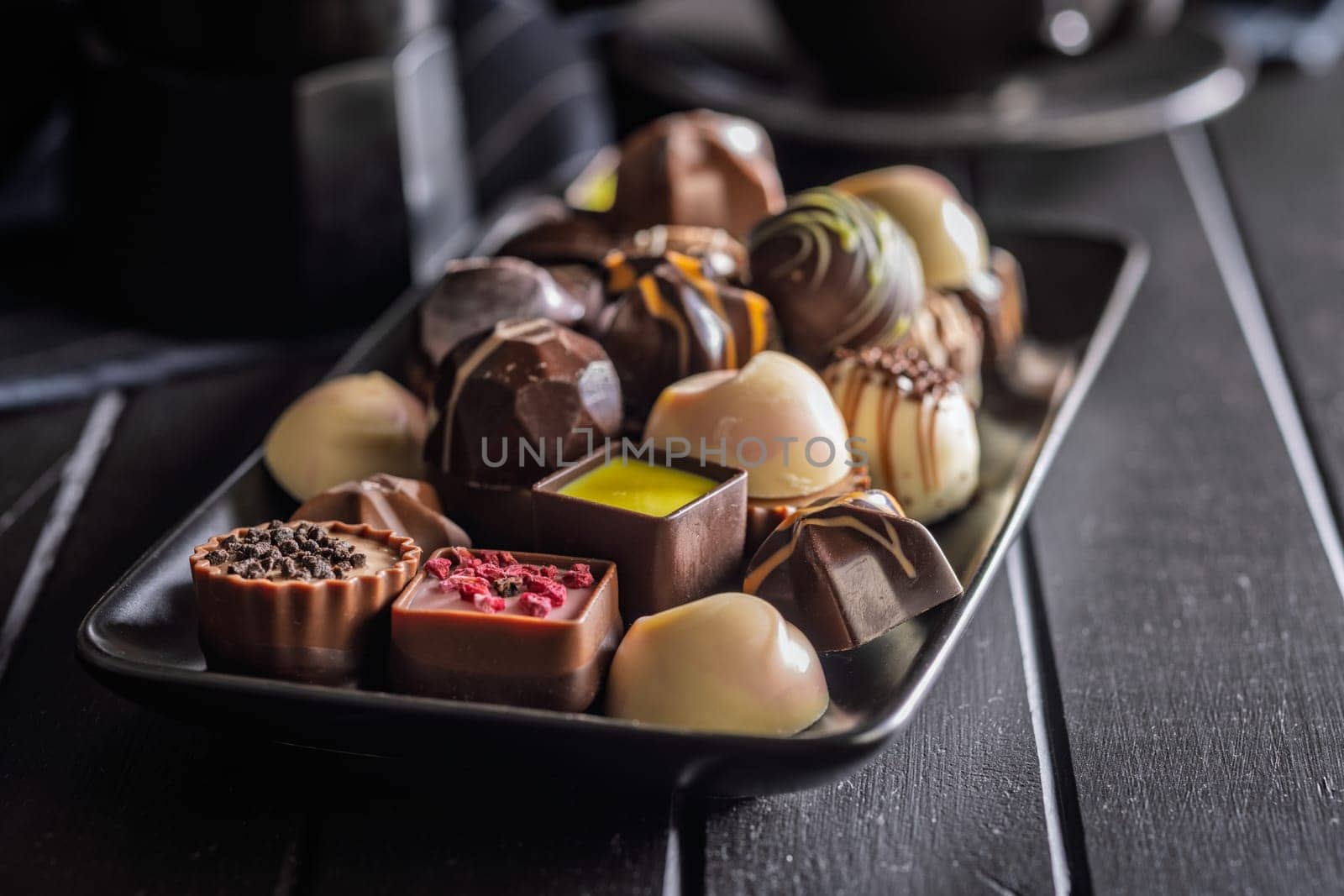 Mix of chocolate pralines on plate on a black table.