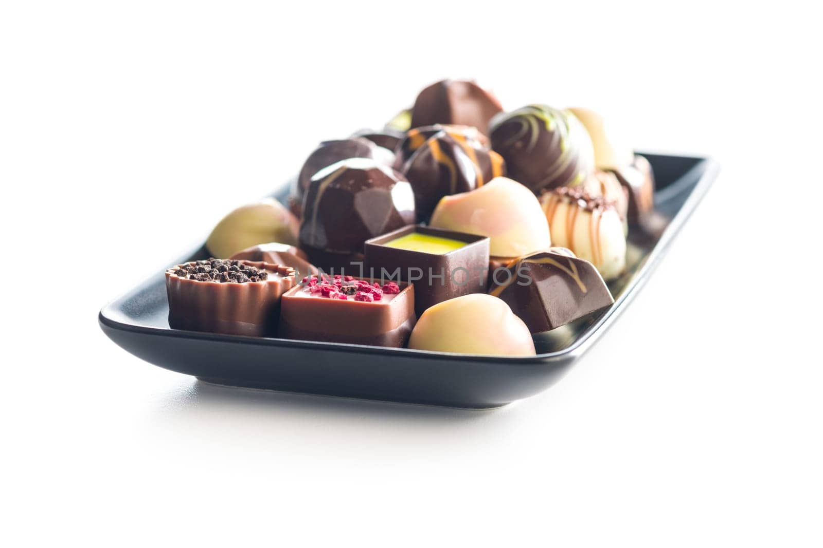 Mix of chocolate pralines on plate isolated on a white background.